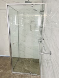 a bathroom with a glass shower stall and tiled floor